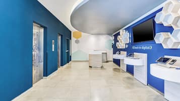 Un área de recepción moderna con una paleta de colores azul y blanco, una estación de registro digital y un diseño minimalista.