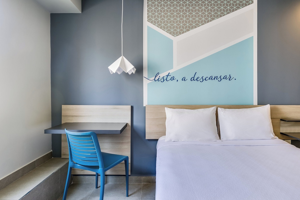 Een moderne hotelkamer met een bed, een bureau en een stoel.