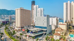 A hotel with multiple floors, a swimming pool, and a view of the city. - One Acapulco Costera (Acapulco)