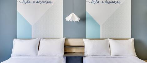 A double bed with white linens, a wooden headboard, and a hanging pendant light.