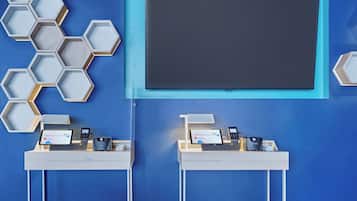 A modern reception desk with a digital screen, a cash register, and a mobile phone.