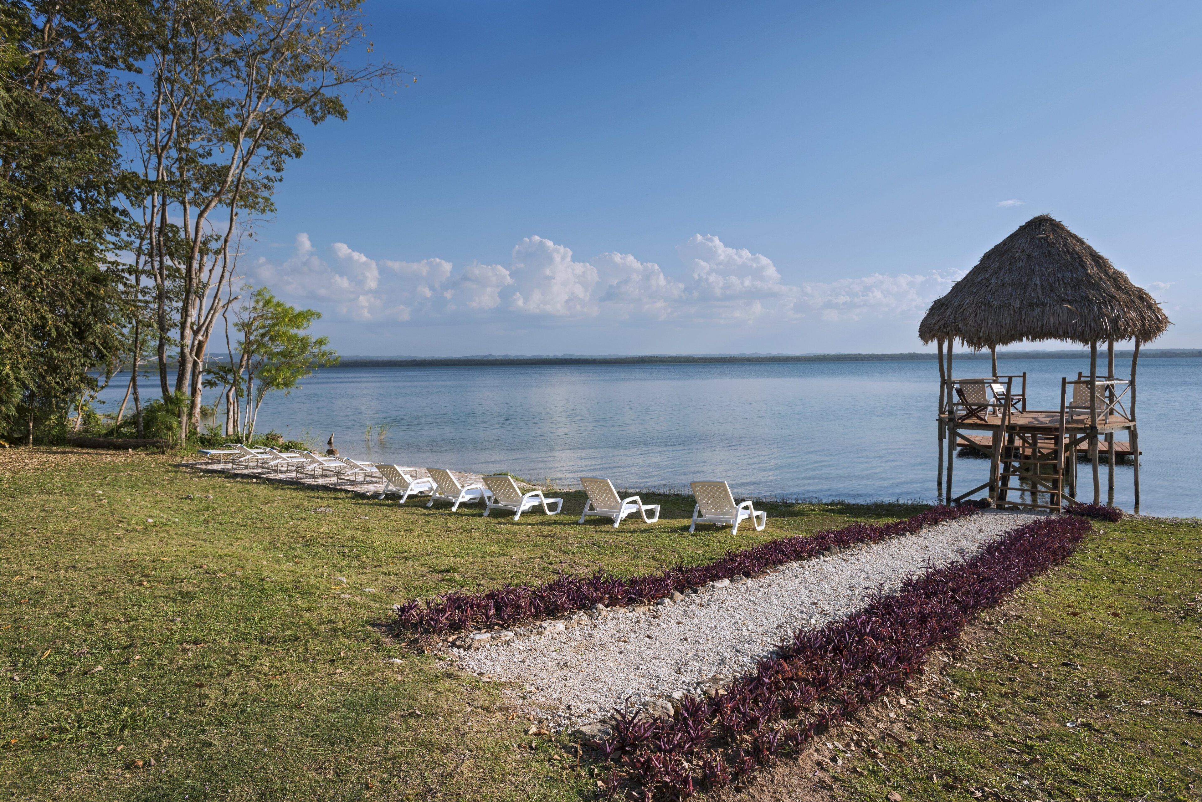 A beachside area with lounge chairs, a thatched-roof structure, and a view of the sea.