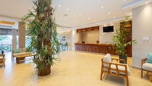 Un hall d’entrée spacieux comprenant un comptoir d’accueil, un espace salon et une grande plante d’intérieur.