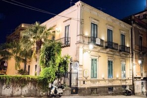 A historic building with a balcony, a scooter parked in front, and a sign indicating a business establishment. - Etnea suite 668 (Catania)