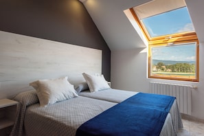 A bedroom with two beds, a skylight, and a view of a green landscape. - Hotel Montemar (O Grove)