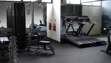 Une salle de sport équipée de tapis de course, d’appareils de musculation et d’un banc.