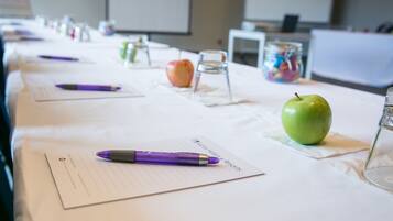 Une table de conférence avec des documents, des stylos et des pommes.