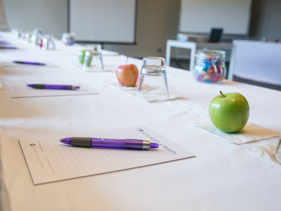 Une table de conférence avec des documents, des stylos et des pommes.