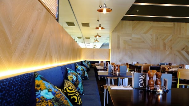 Un restaurante con una barra larga, asientos tapizados en azul y paredes de madera.