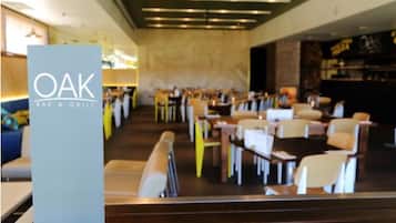 A restaurant interior with a modern design, featuring a bar area and multiple dining tables and chairs.