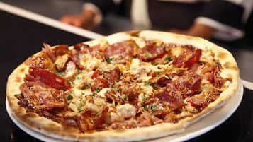 Una pizza con pepperoni y pollo sobre un plato blanco.