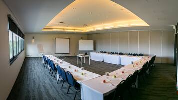 A conference room with a long table, chairs, a whiteboard, and a projector screen.