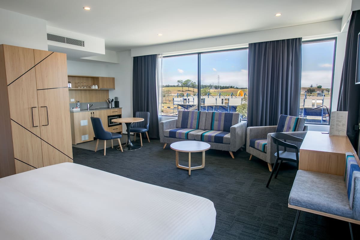 Ein modernes Hotelzimmer mit einem großen Bett, einer Couch, einem Esstisch und einer Küchenzeile.
