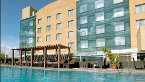 A hotel with a swimming pool, a covered seating area, and a modern building facade. - Royal Orchid Central Pune (Pune)