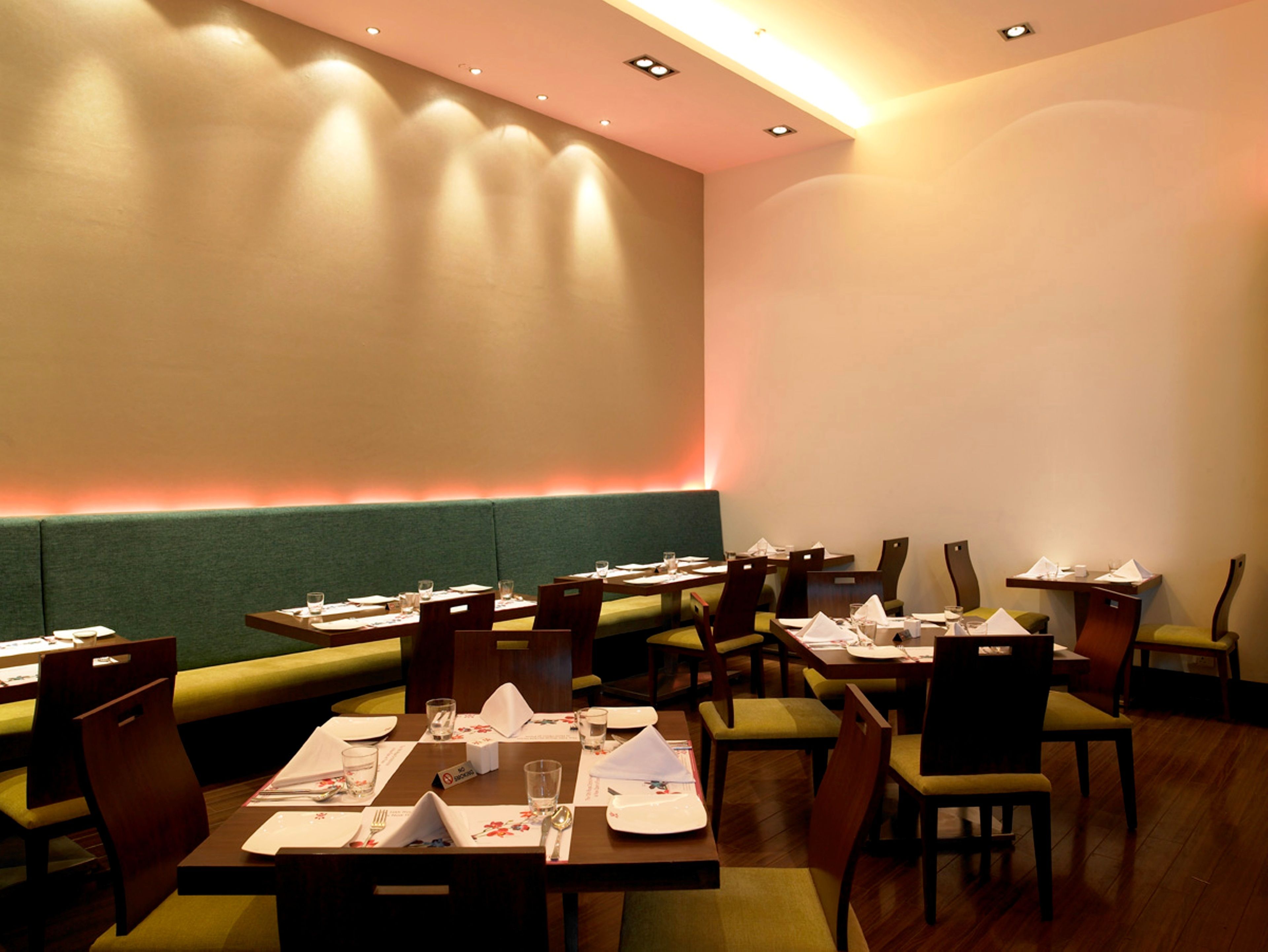 Un restaurante con cabinas y mesas, algunas con cojines verdes.