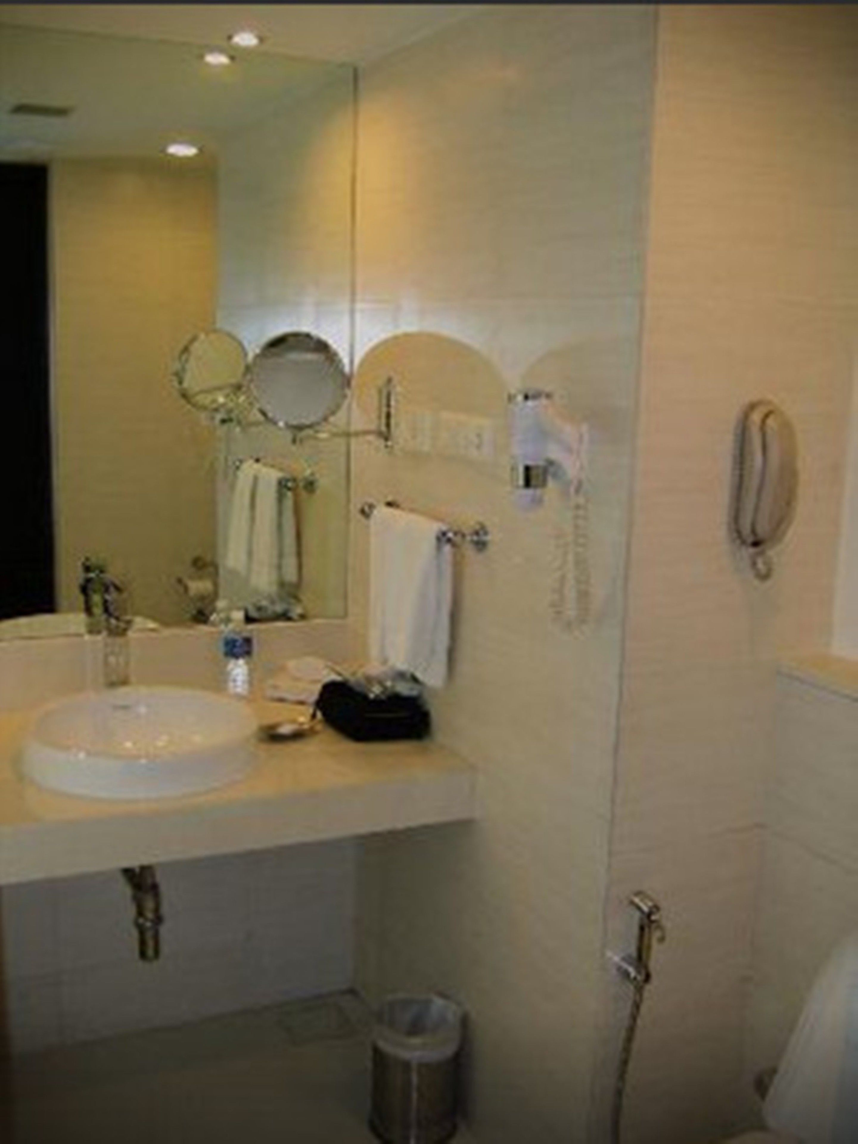 Un baño con lavamanos, espejo, toallero y teléfono.