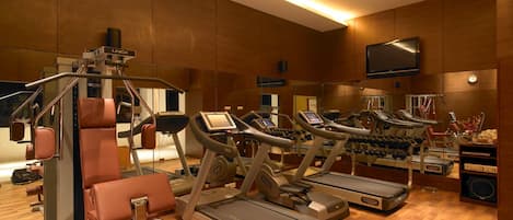 A gym with treadmills, weight machines, and a mirrored wall.