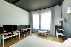 Una habitación de hotel con una cama, televisión, escritorio y una silla.