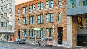 A multi-story building with a brick facade, large windows, and a sign indicating a hotel. - Hôtel du Jardin by Les Lofts Vieux-Quebec (Québec City)