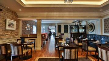 A spacious hotel lobby with wooden flooring, multiple seating areas, and a central hallway leading to other parts of the hotel.