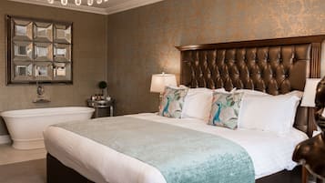 A spacious bedroom with a large bed, a separate bathtub, and a decorative mirror on the wall.