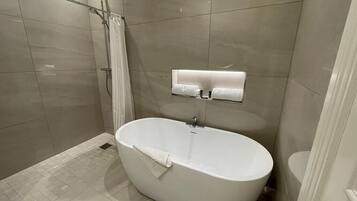 A modern bathroom with a freestanding bathtub, a shower area, and a built-in vanity with a mirror.
