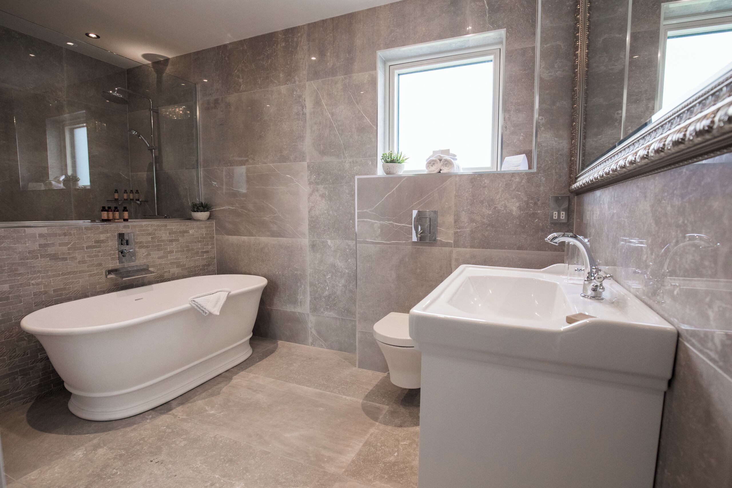 A modern bathroom with a freestanding bathtub, a pedestal sink, and a toilet.