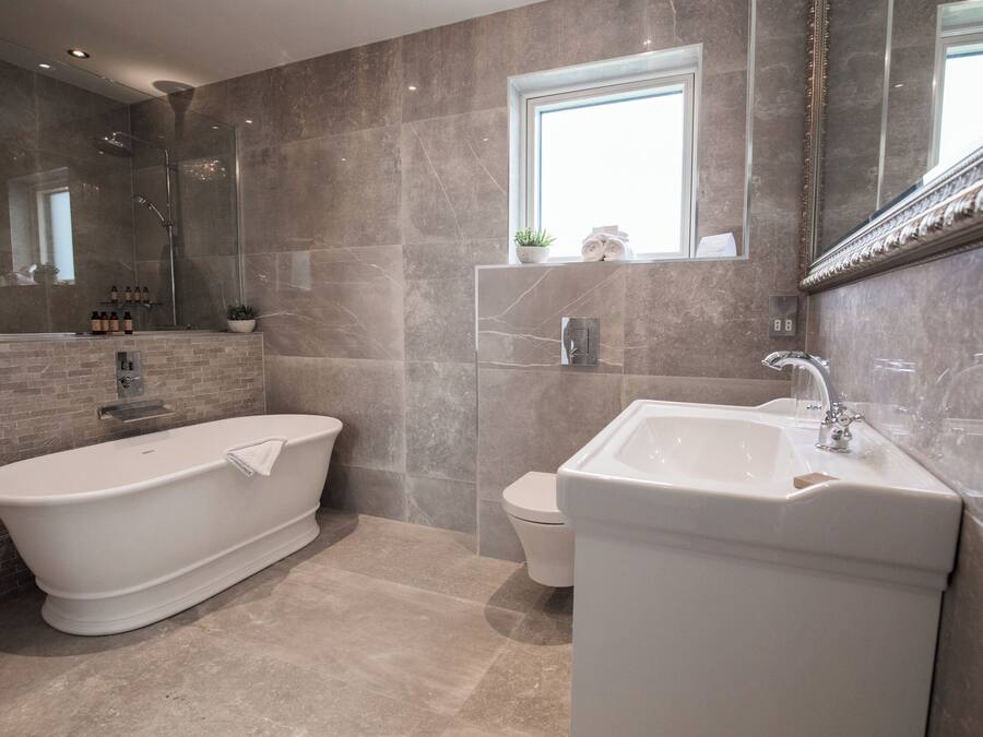 A modern bathroom with a freestanding bathtub, a pedestal sink, and a toilet.