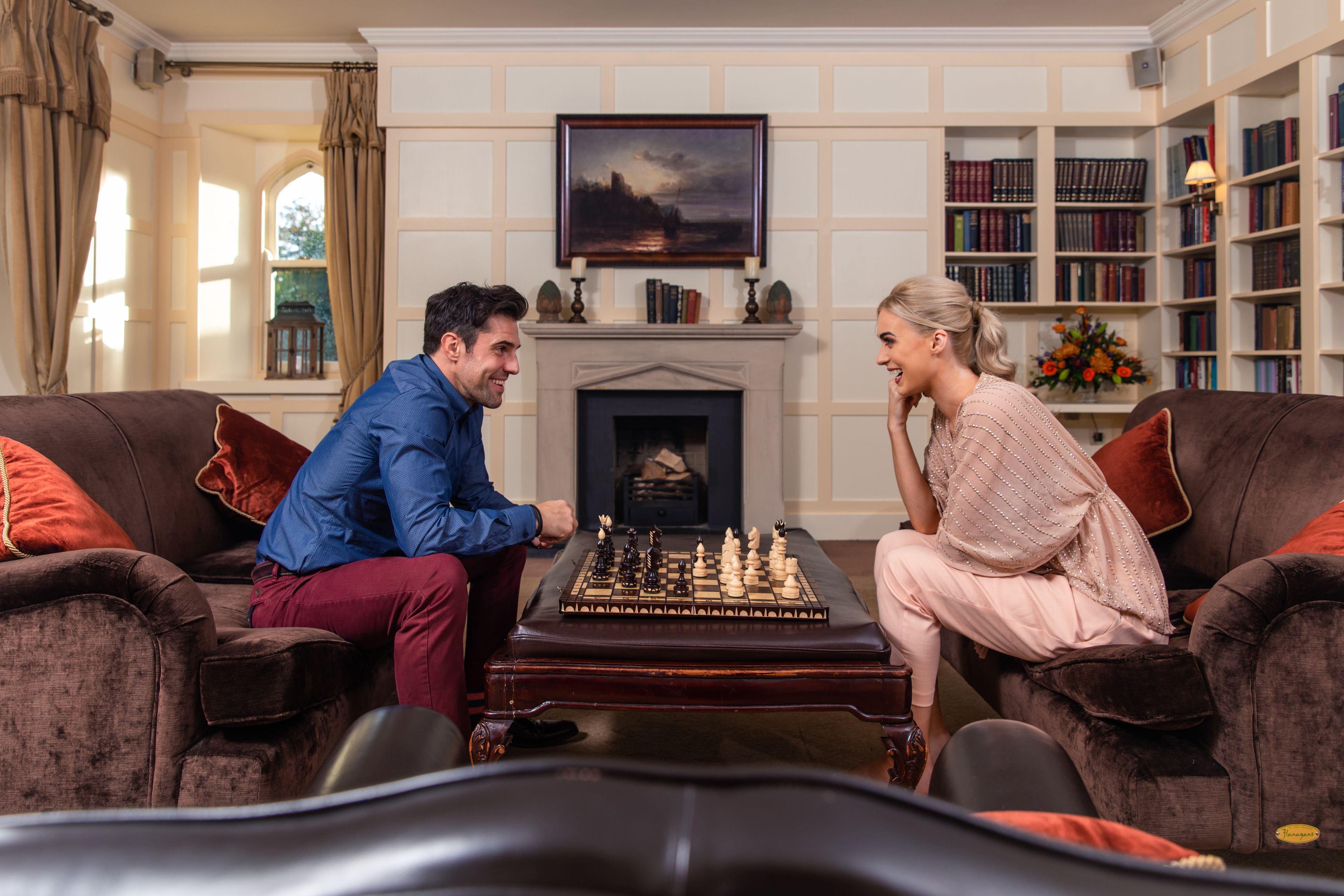 A room with a fireplace, a chessboard, and a bookshelf.