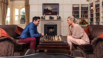 A room with a fireplace, a chessboard, and a bookshelf.