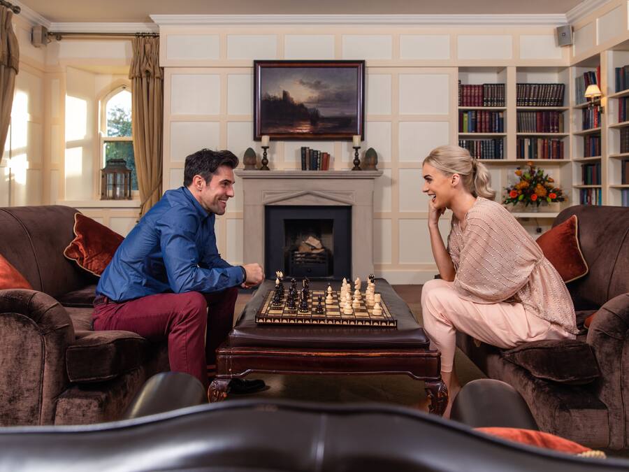A room with a fireplace, a chessboard, and a bookshelf.