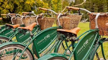 Una hilera de bicicletas verdes con cestas de mimbre y asientos de cuero, identificadas como "Lough Eske Castle".