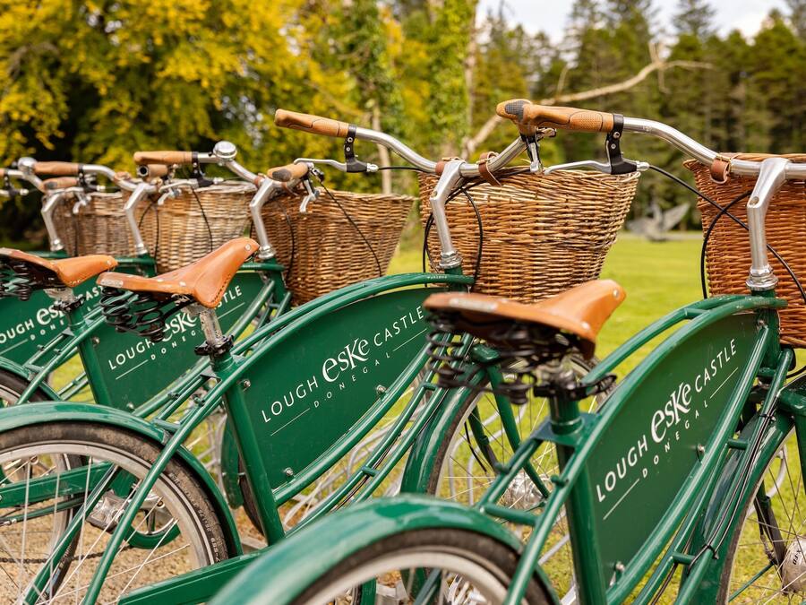 Una hilera de bicicletas verdes con cestas de mimbre y asientos de cuero, identificadas como "Lough Eske Castle".