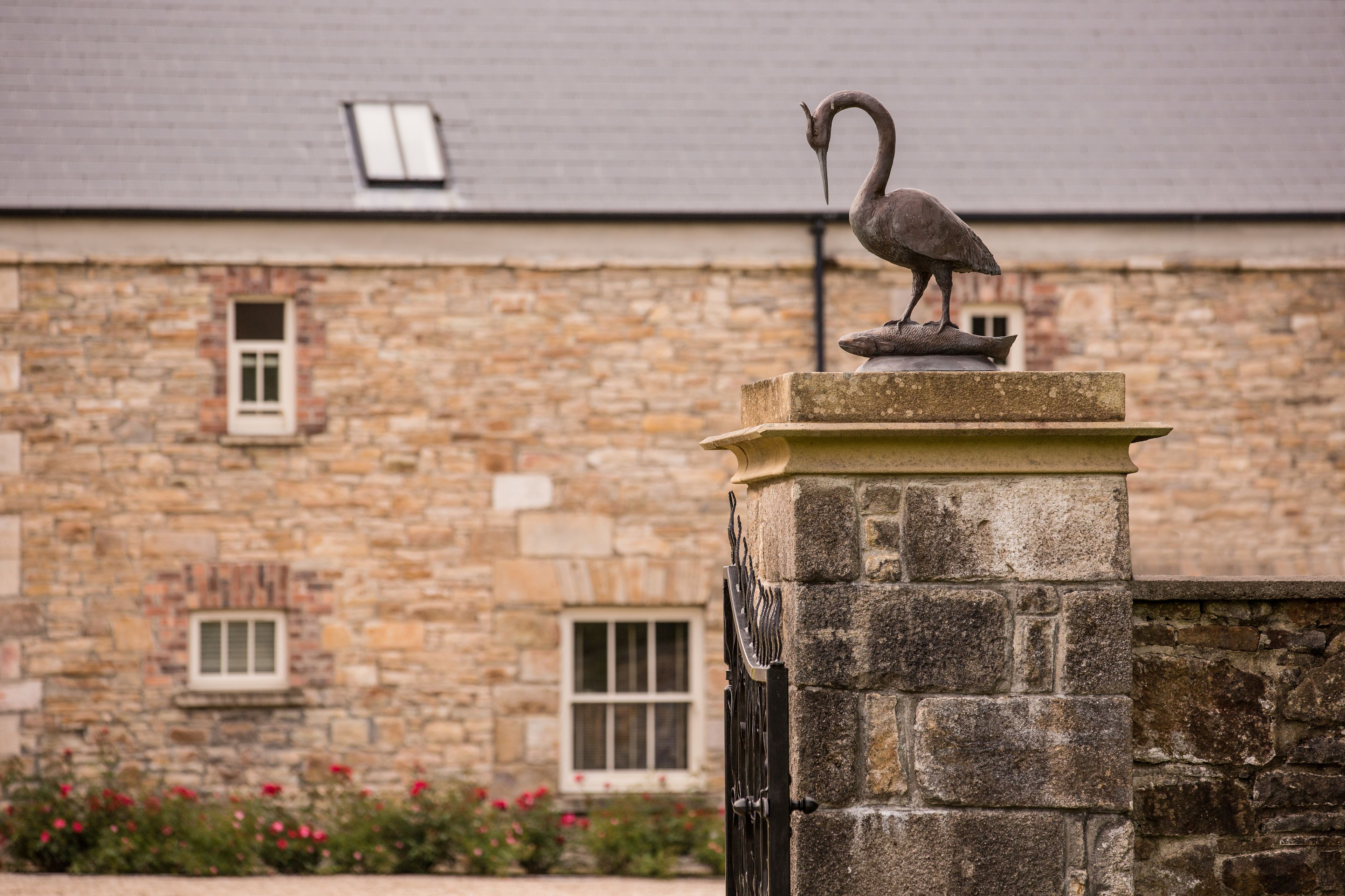 A stone building with a statue of a bird on a pedestal.