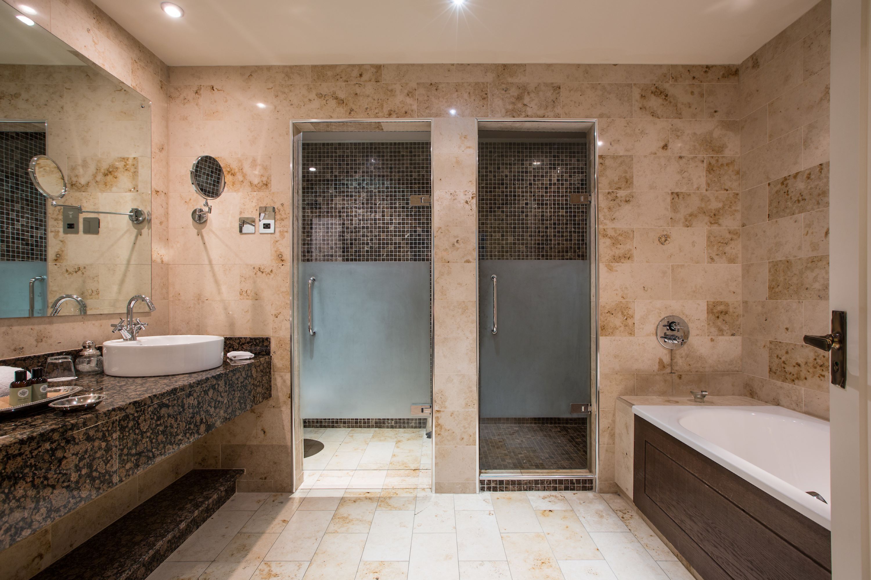 Un baño moderno con un lavamanos grande, una bañera y una ducha con cerramiento de vidrio.