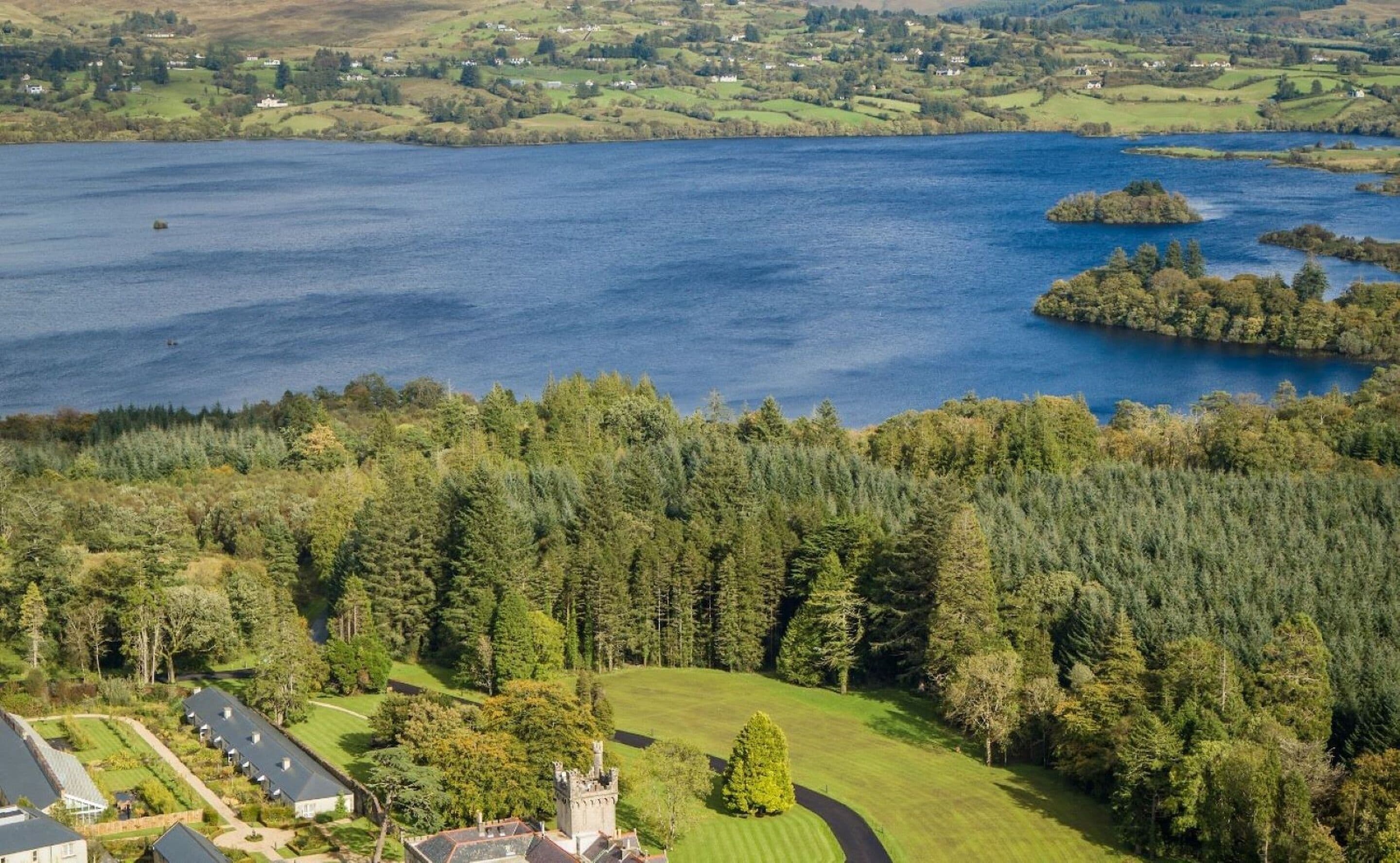 A large body of water with a forested area and a castle-like structure in the foreground.