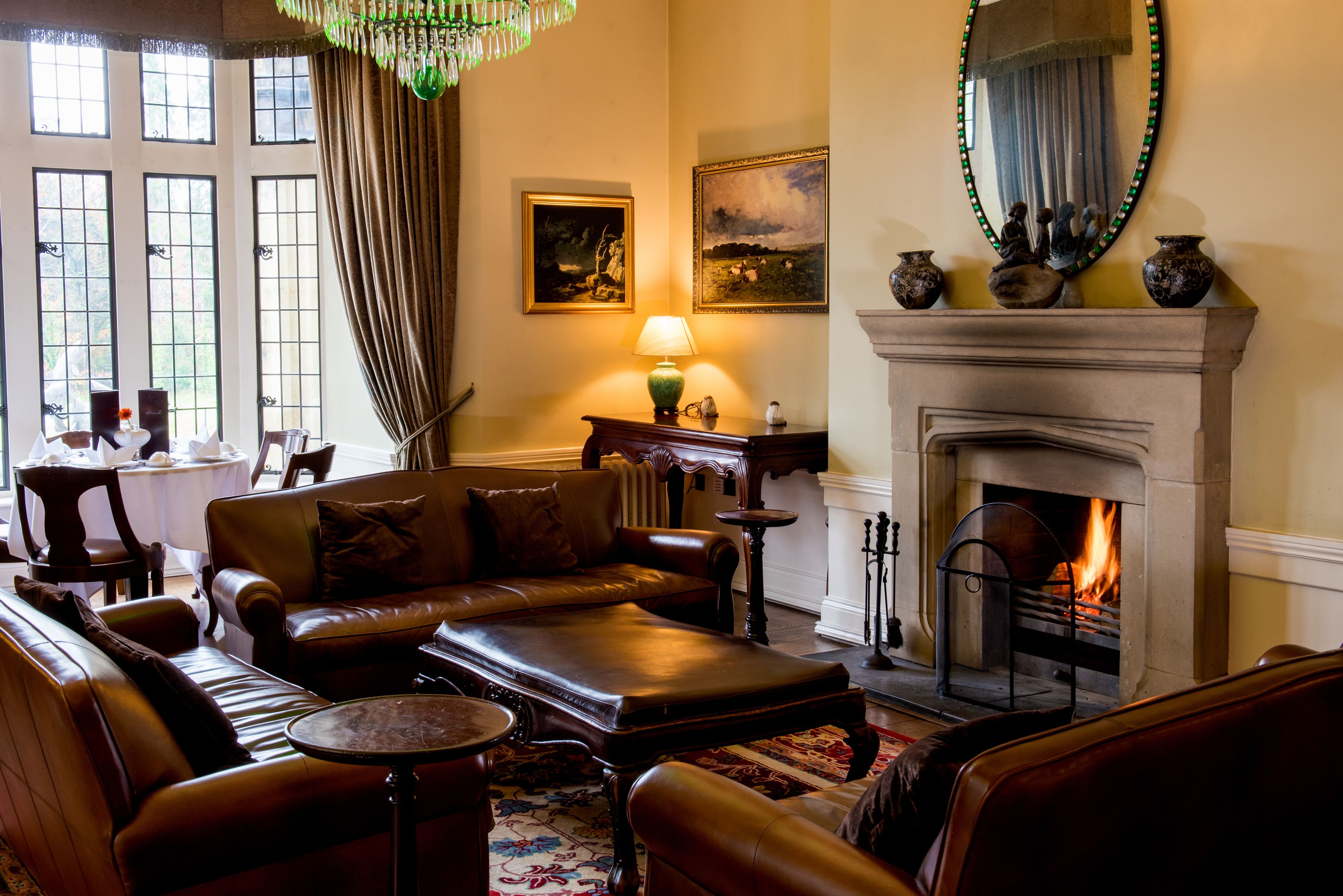 A cozy living room with a leather sofa, a fireplace, and a table with a lamp.