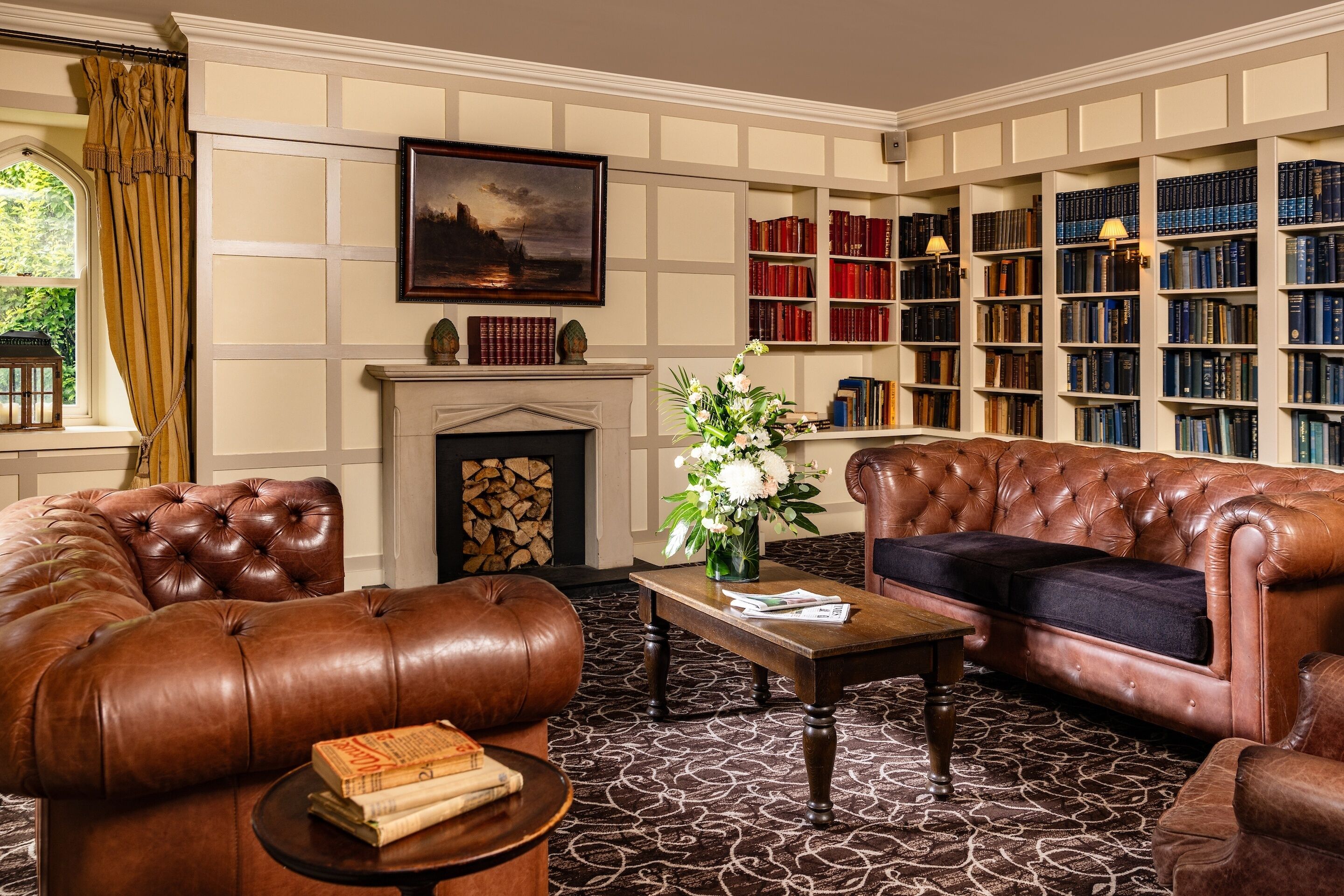 A library with leather sofas, a fireplace, and bookshelves.