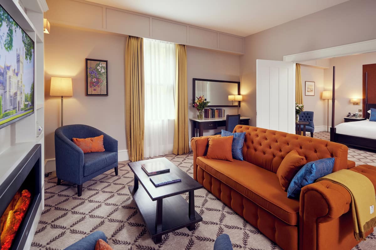 A hotel room with a sofa, armchair, coffee table, and a bed.