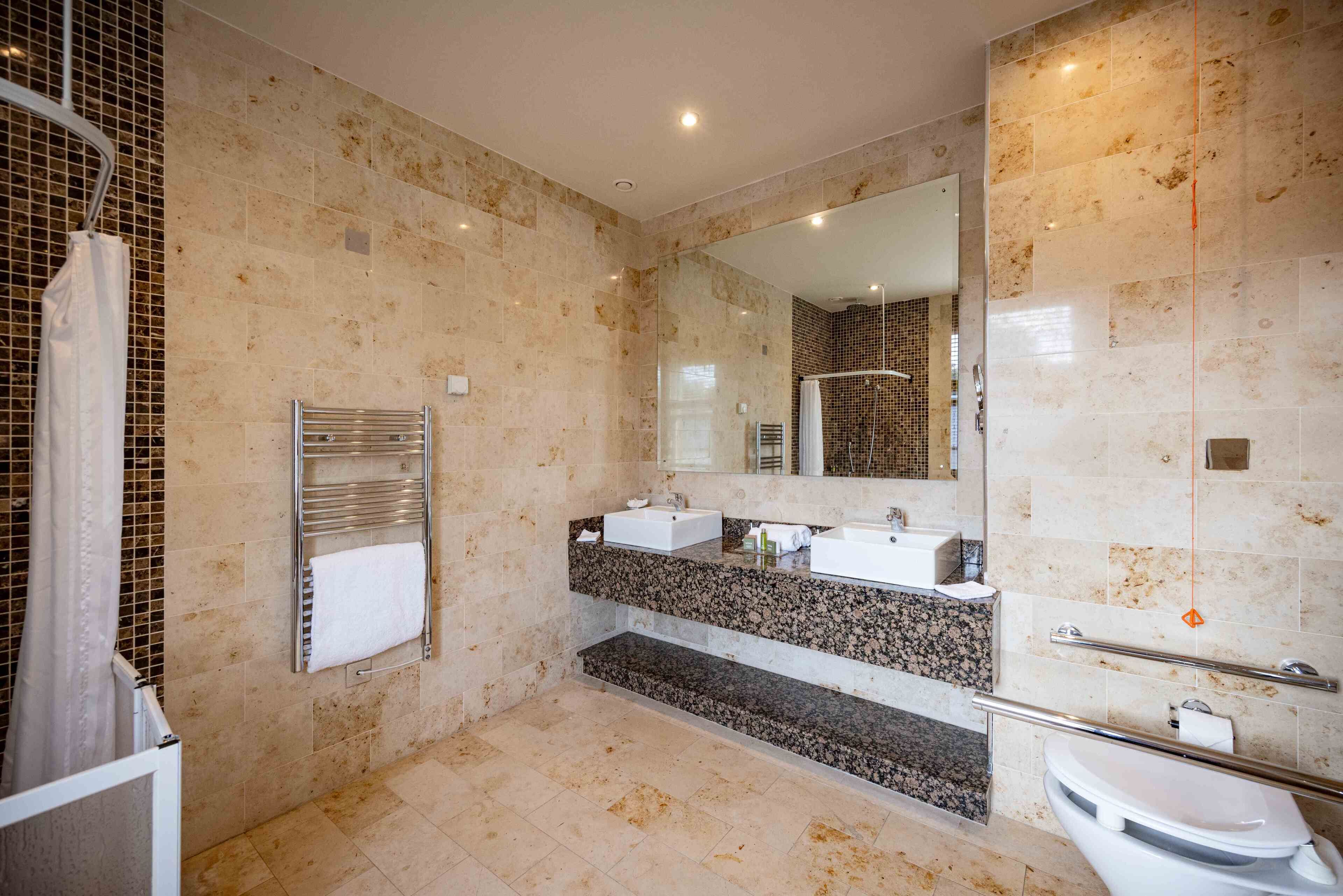 Un baño moderno con dos lavamanos, una ducha y un inodoro.