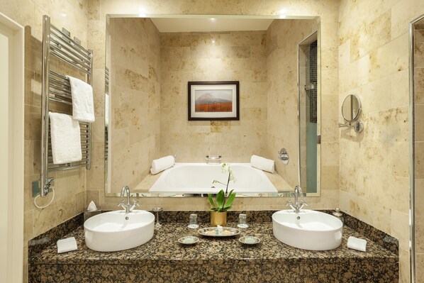 A modern bathroom with two sinks, a large mirror, a framed picture on the wall, and a towel rack.