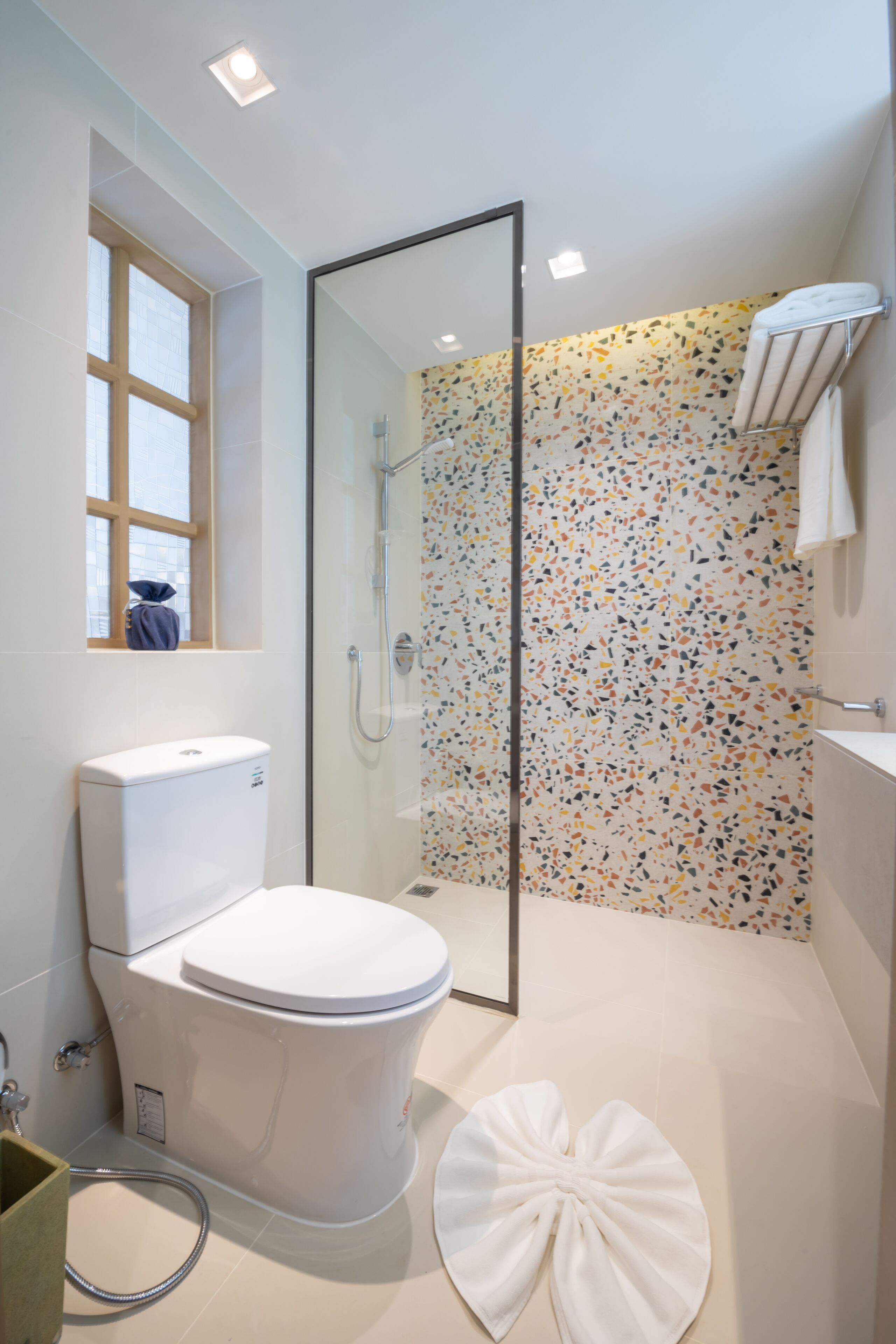 A modern bathroom with a toilet, shower, and a decorative wall.