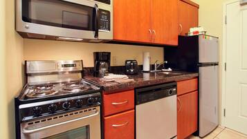 A kitchen with stainless steel appliances, wooden cabinets, and a white refrigerator.