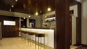 Zona de bar con mostrador, taburetes y una máquina de café.