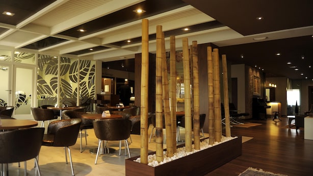 Un interior moderno con una zona de recepción, arreglos de asientos y una decoración de bambú.