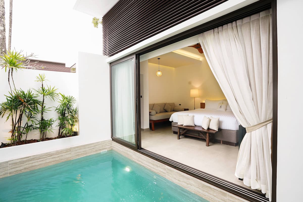 A modern hotel room with a glass door leading to a balcony with a pool.