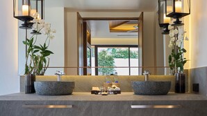 A modern bathroom with a large mirror, two stone basins, and hanging lanterns.