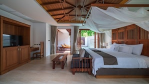 A bedroom with a bed, bedside table, and a TV on a wooden cabinet. - Malisa Villa Suites (Karon)