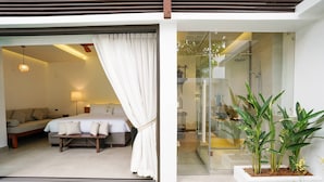 A modern bedroom with a large bed, a bedside table, and a glass shower enclosure.