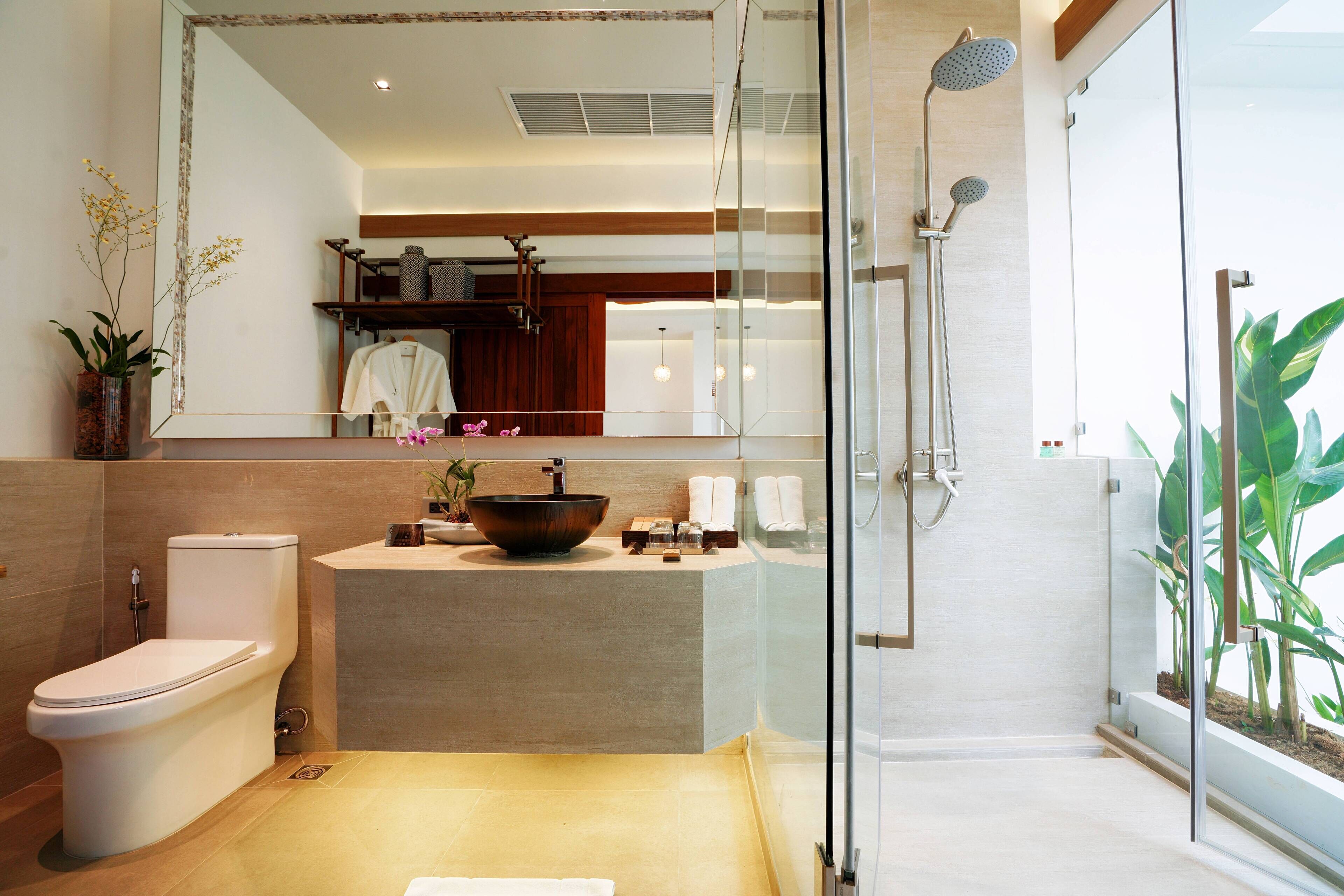A modern bathroom with a glass-enclosed shower, a large mirror, a vessel sink, and a toilet.